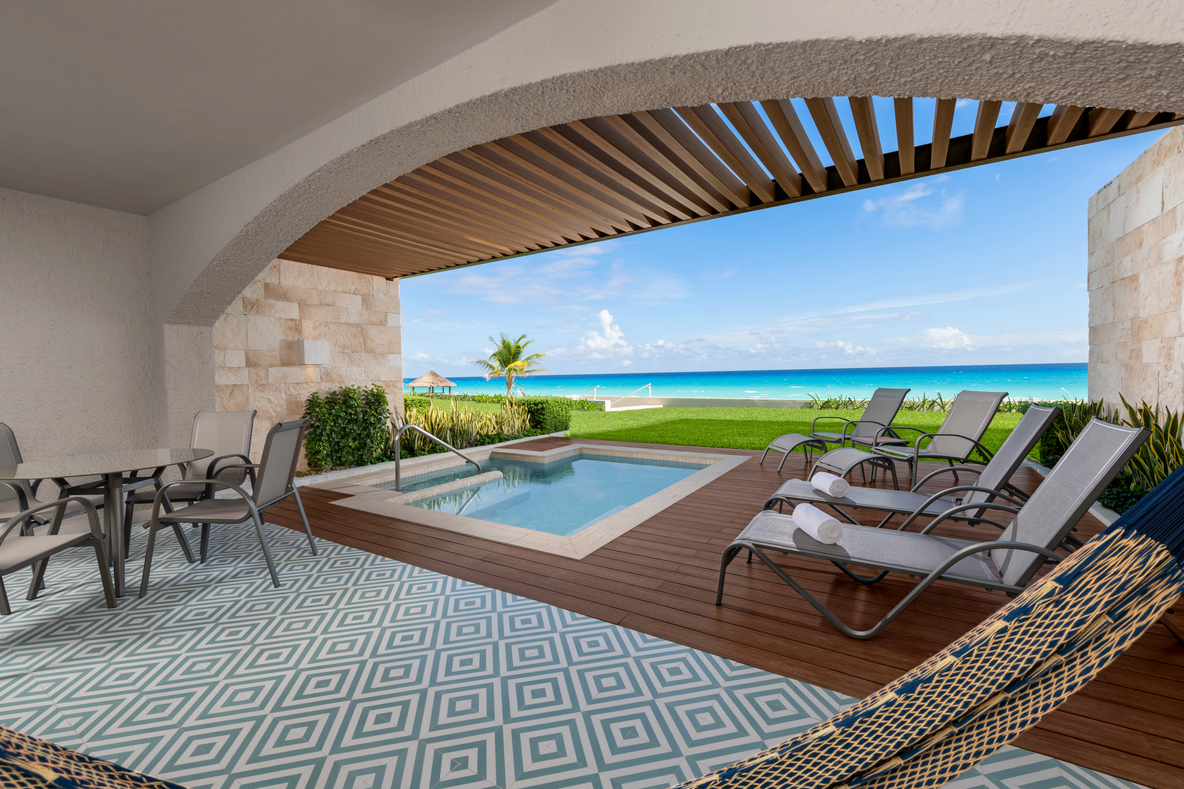 plunge pool area with table and chairs, lounge chairs, and ocean view